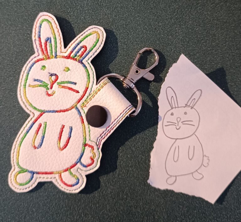 Porte-clés lapin brodé posé à côté du dessin original